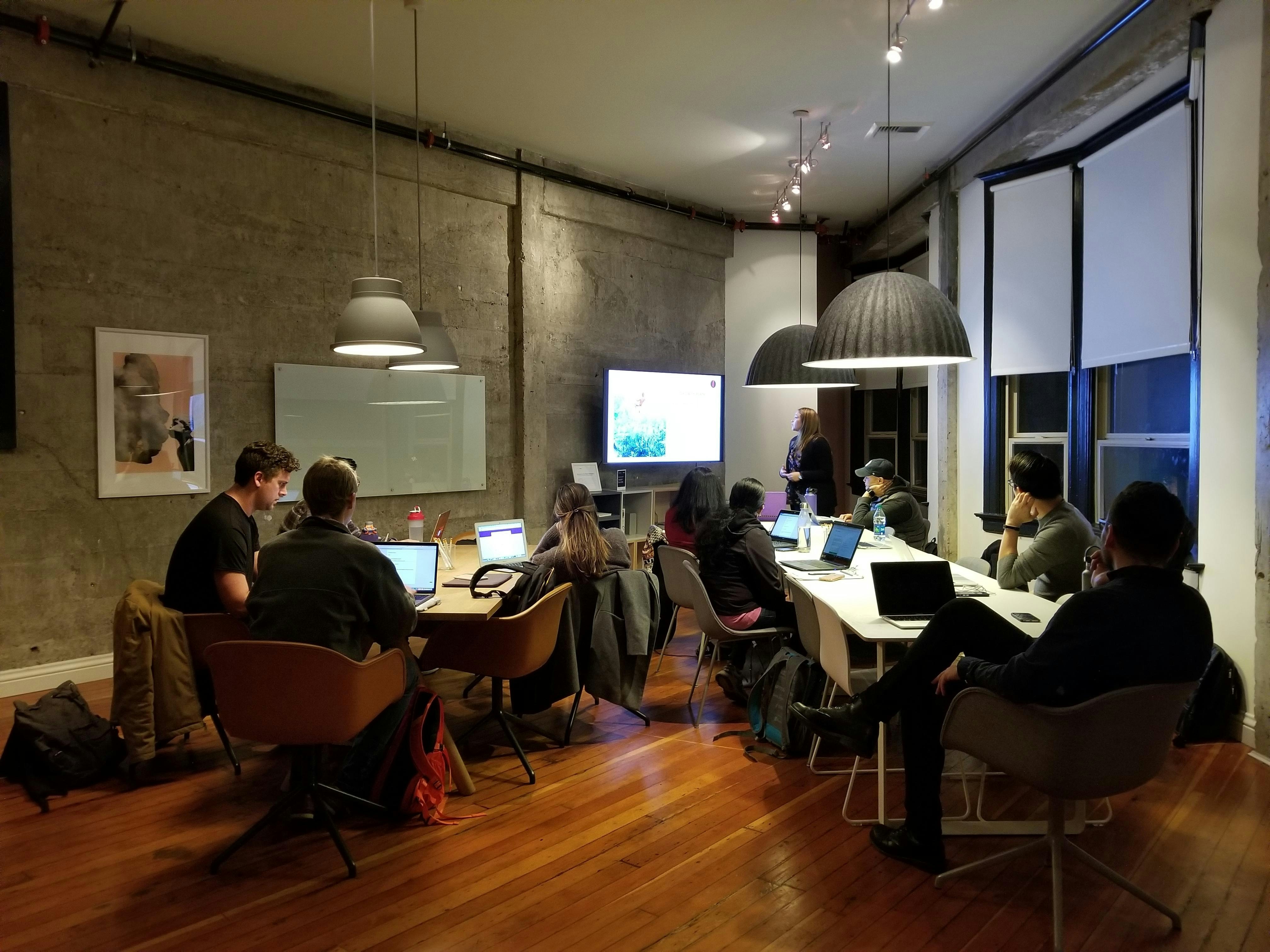 Team collaborating in a modern workshop space with laptops and presentation screen